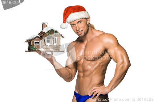 Image of Attractive young muscle man smiling in Santa Claus\'s red hat