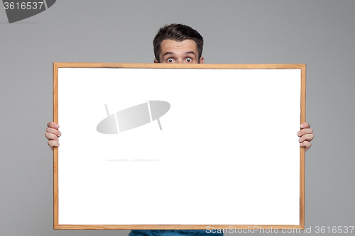 Image of The surprised man showing empty white billboard or banner on gray background