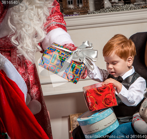 Image of holidays and people concept - smiling little boy with santa claus 