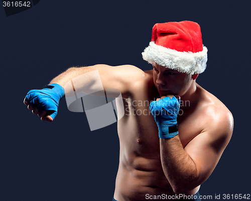 Image of Christmas fitness boxer wearing santa hat boxing on black 