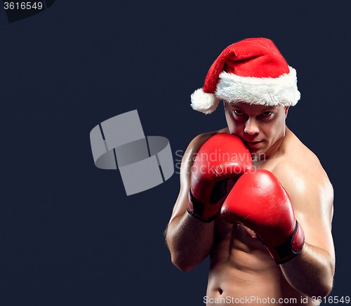 Image of Christmas fitness boxer wearing santa hat boxing on black background