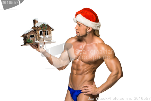 Image of Attractive young muscle man smiling in Santa Claus\'s red hat