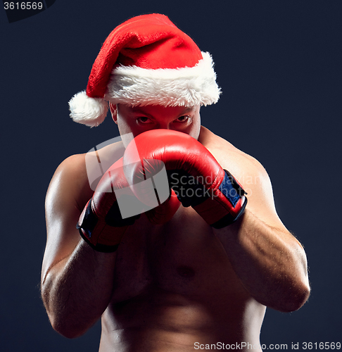 Image of Christmas fitness boxer wearing santa hat boxing on black background
