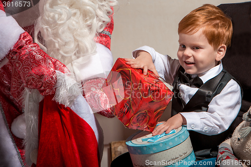 Image of holidays and people concept - smiling little boy with santa claus 