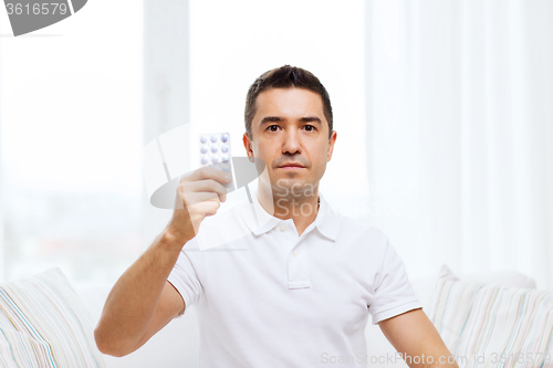 Image of man showing pack of pills at home