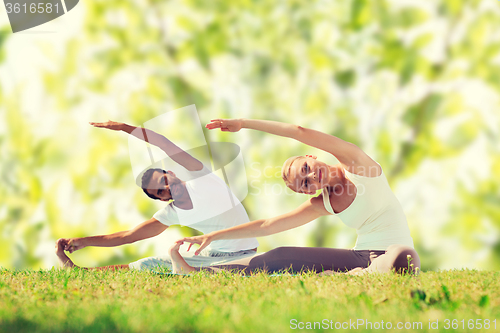 Image of happy couple stretching and doing yoga exercises