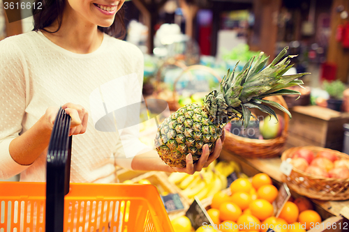 Image of close up of woman with pineapple in grocery market