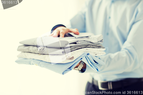 Image of close up of businessman holding folded shirts