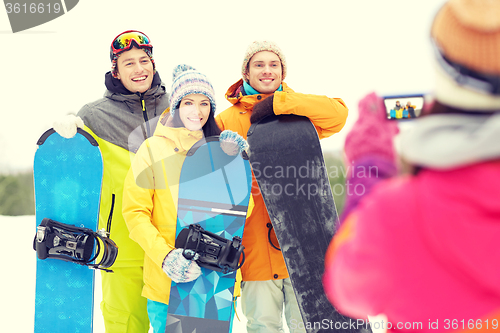 Image of happy friends with snowboards and smartphone