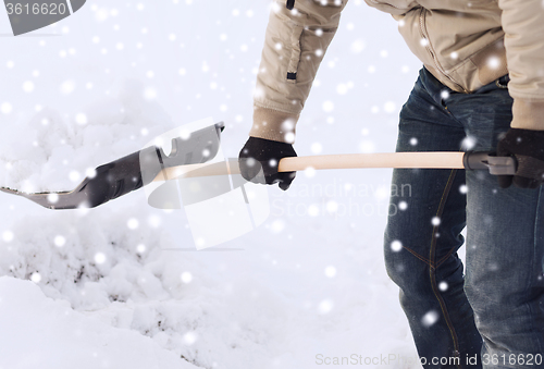 Image of closeup of man digging snow with shovel