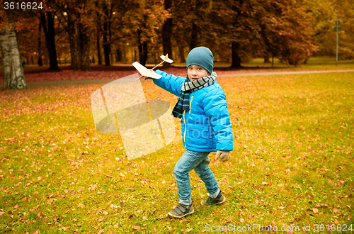 Image of happy little boy playing with toy plane outdoors