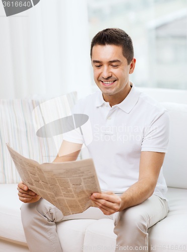 Image of happy man reading newspaper at home