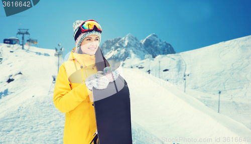 Image of happy young woman with snowboard over mountains