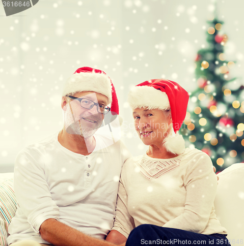Image of happy senior couple in santa helper hats at home