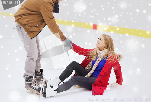 Image of man helping women to rise up on skating rink