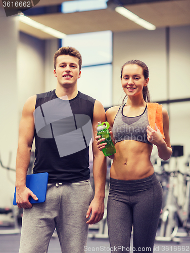 Image of happy couple in gym with water and tablet pc