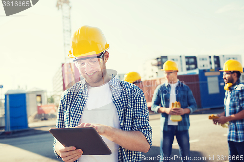 Image of smiling builders in hardhats with tablet pc