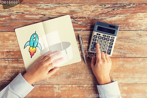 Image of close up of hands with calculator and notebook