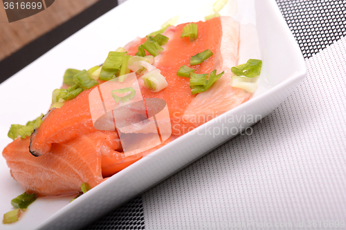 Image of Salted salmon fillet with parsley leaf on the white bowl