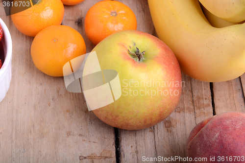 Image of Mandarin Apples Bananas Peach on wooden plate