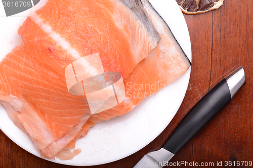 Image of Raw salmon fish steaks with fresh herbs on white plate