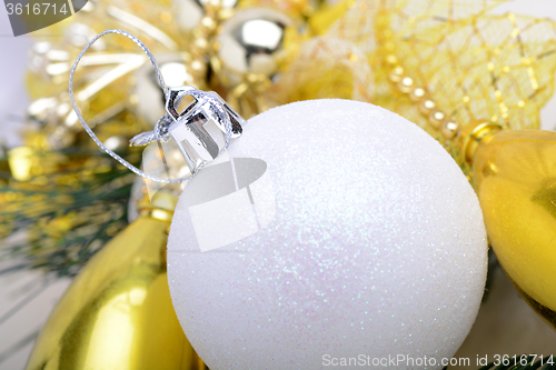 Image of festive golden christmas decoration, candles, white balls, green fir tree branch, close up