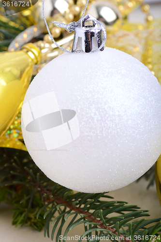 Image of festive golden christmas decoration, candles, white balls, green fir tree branch, close up