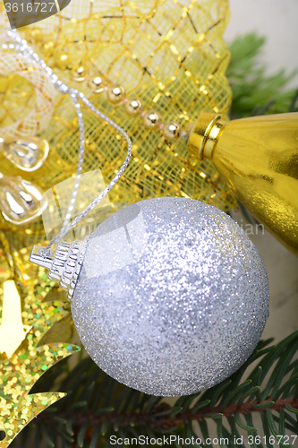 Image of festive golden christmas decoration, candles, white balls, green fir tree branch, close up