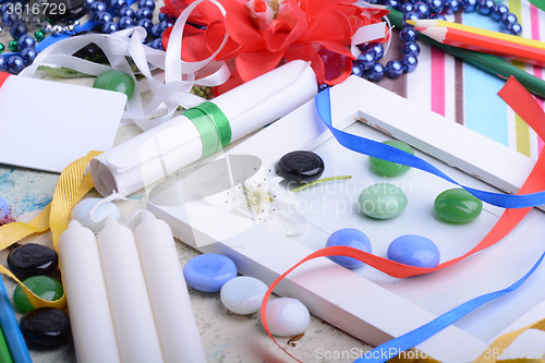 Image of Interior design table with a gift and a bow. candle and diamonds set. Gift box with pearls. white wooden frame. Background for a card