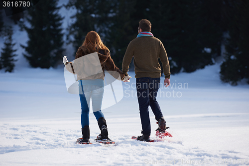 Image of couple having fun and walking in snow shoes