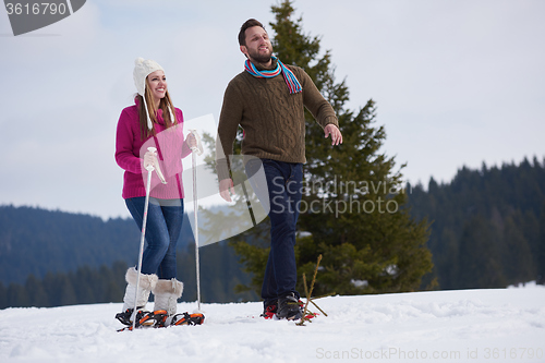 Image of couple having fun and walking in snow shoes