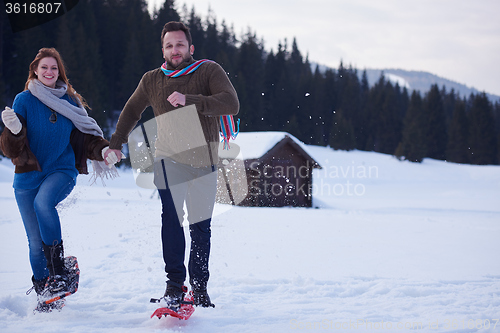 Image of couple having fun and walking in snow shoes