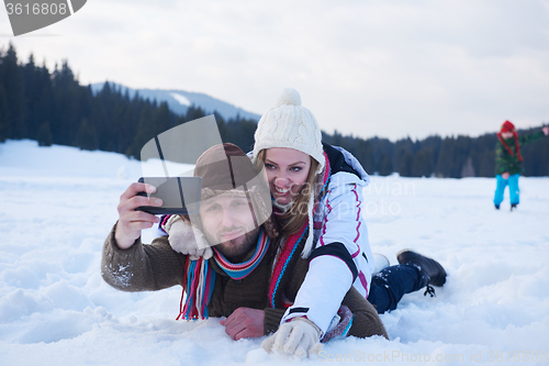 Image of romantic couple have fun in fresh snow and taking selfie
