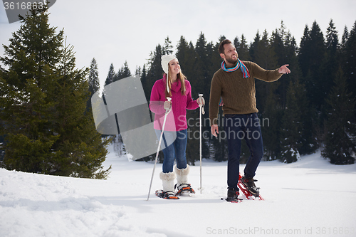 Image of couple having fun and walking in snow shoes