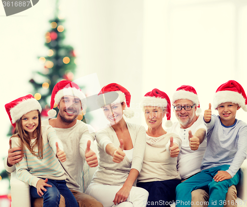 Image of happy family in santa hats showing thumbs up