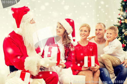 Image of smiling family with santa claus and gifts at home