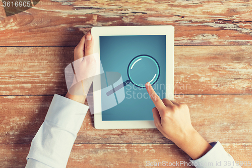 Image of close up of male hands with magnifier on tablet pc