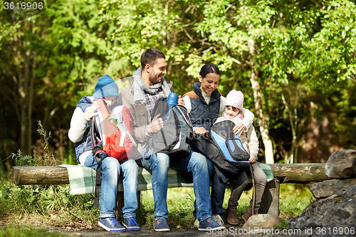 Image of happy family with backpacks and thermos at camp