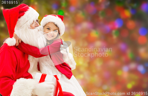 Image of smiling girl cuddling with santa claus over lights