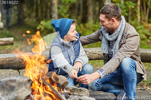 Image of father and son roasting marshmallow over campfire