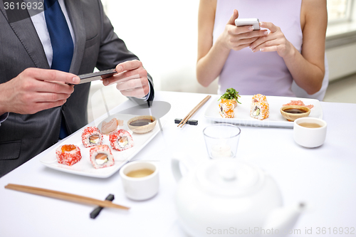 Image of close up of couple with smartphones at restaurant