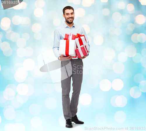 Image of happy young man holding gift boxes