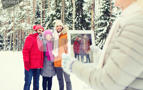 Image of smiling friends with tablet pc in winter forest