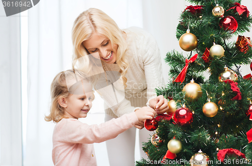 Image of happy family decorating christmas tree at home