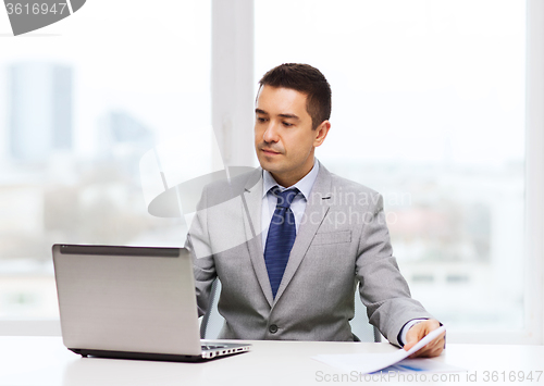 Image of businessman with laptop and papers