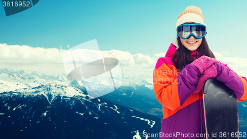 Image of happy young woman with snowboard over mountains