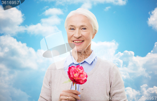 Image of happy smiling senior woman with flower at home