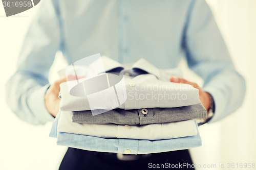 Image of close up of businessman holding folded shirts