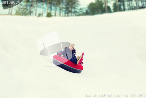 Image of happy teenage girl sliding down on snow tube