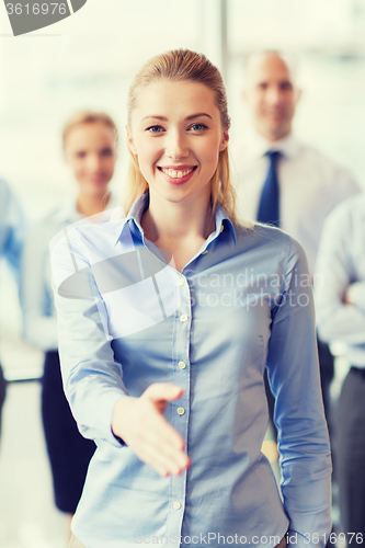 Image of smiling businesswoman making handshake in office